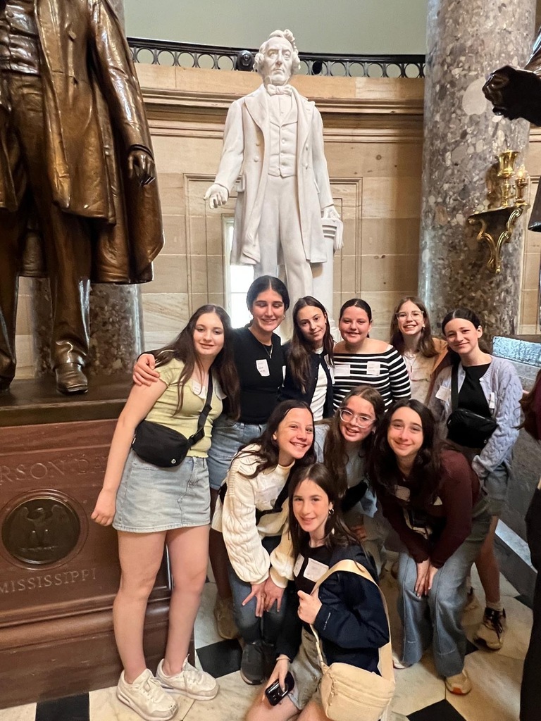 seventh grade students pose in front of statue at museum