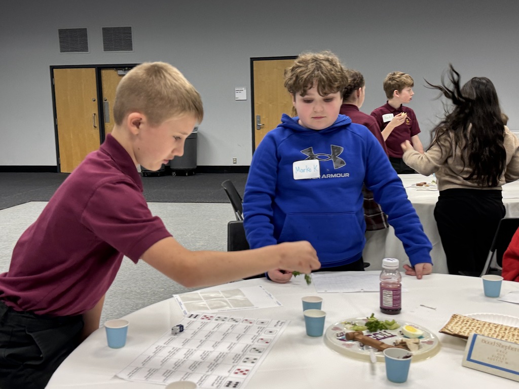 Smith student instructs Good Shepherd student to dip parsley into salt water
