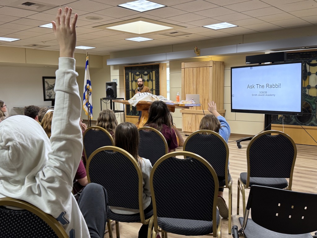 students raise hands in Ask the Rabbi session