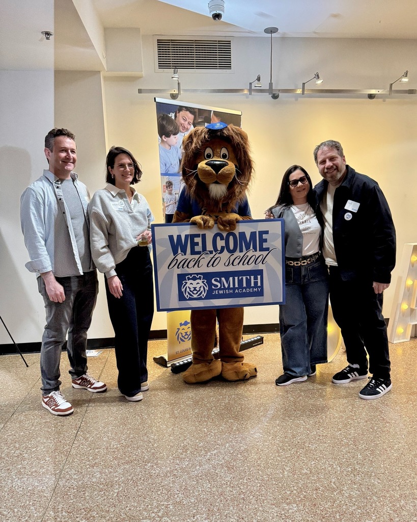 guests pose with Roary the Lion mascot and welcome back to school sign