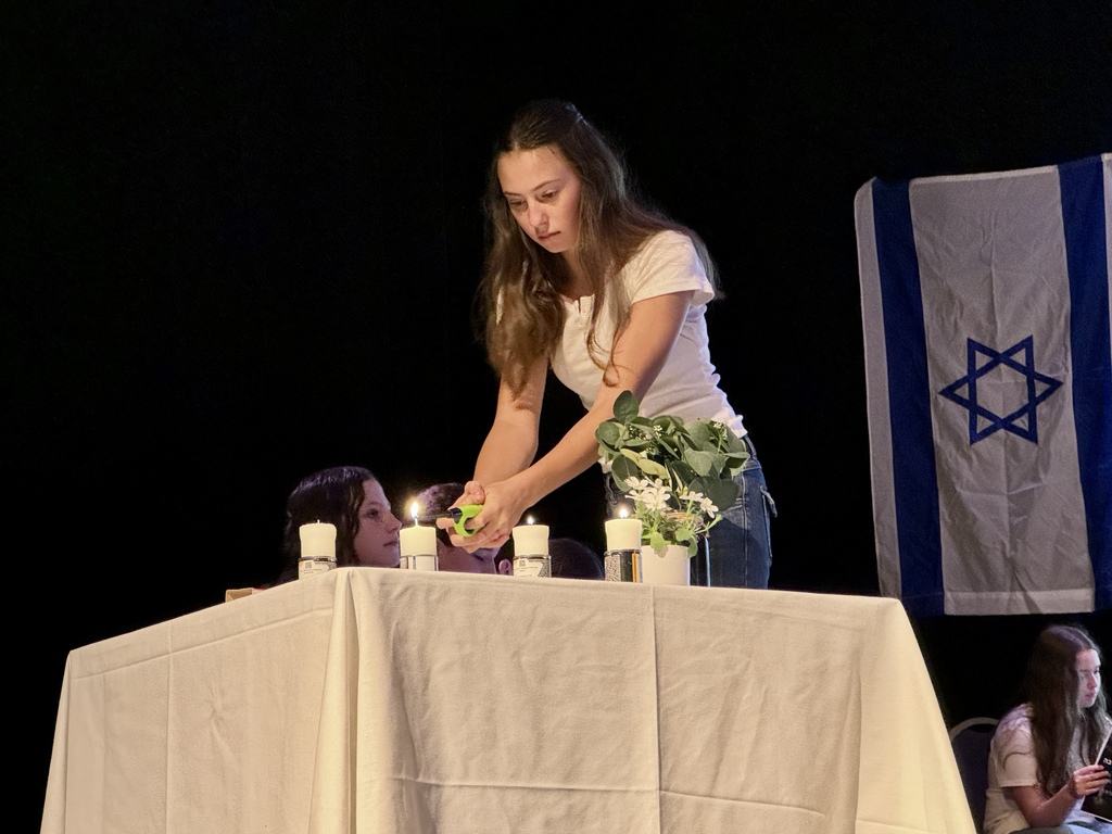 student lights yahrzeit candle