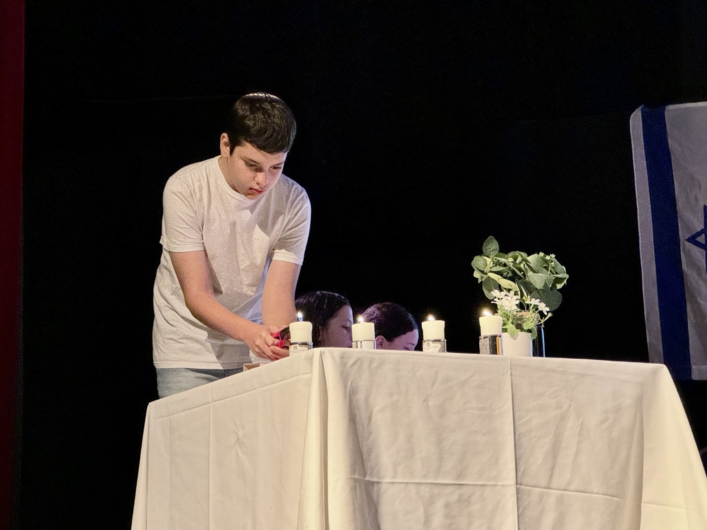 student lights yahrzeit candle
