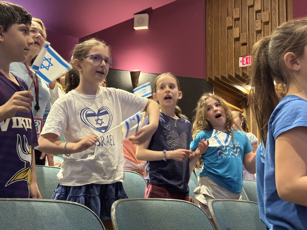 students sing and wave Israeli flags
