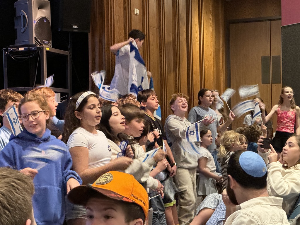students sing and wave Israeli flags