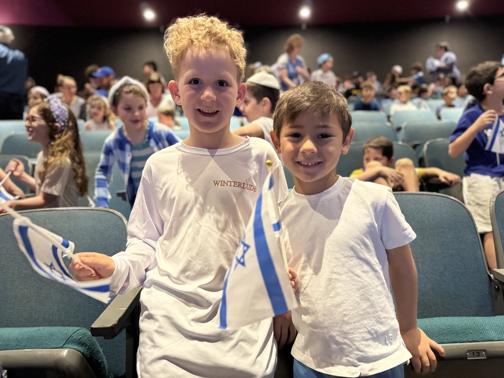 two students pose smiling with Israeli flags