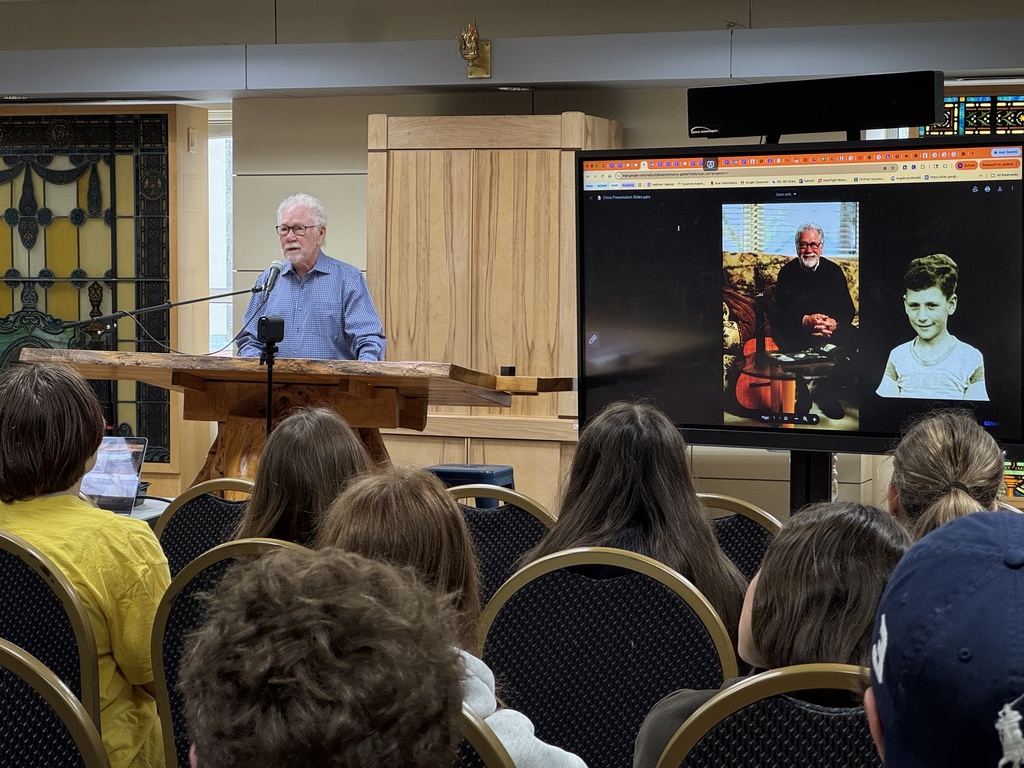 Manny Gabler speaks at podium to middle school students