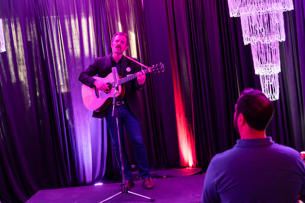 musician sings and plays guitar  for audience