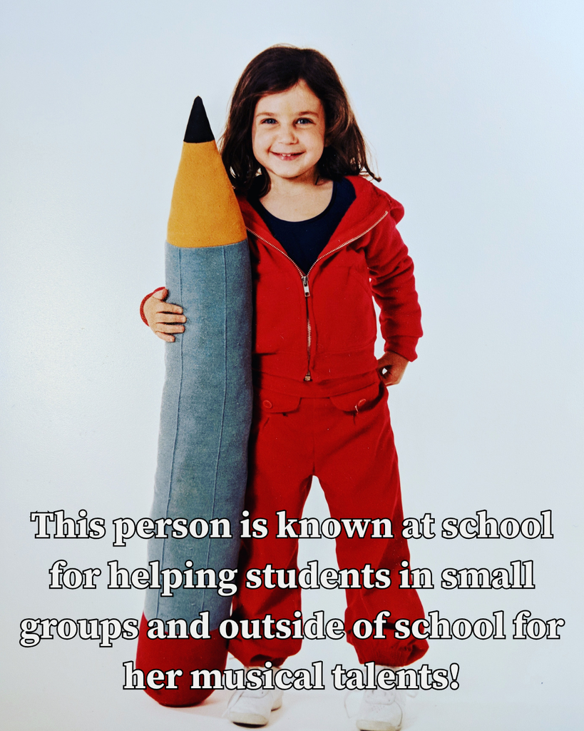 little girl in red track suit holding plush pencil as tall as she is: This person is known at school for helping students in small groups and outside of school for her musical talents!