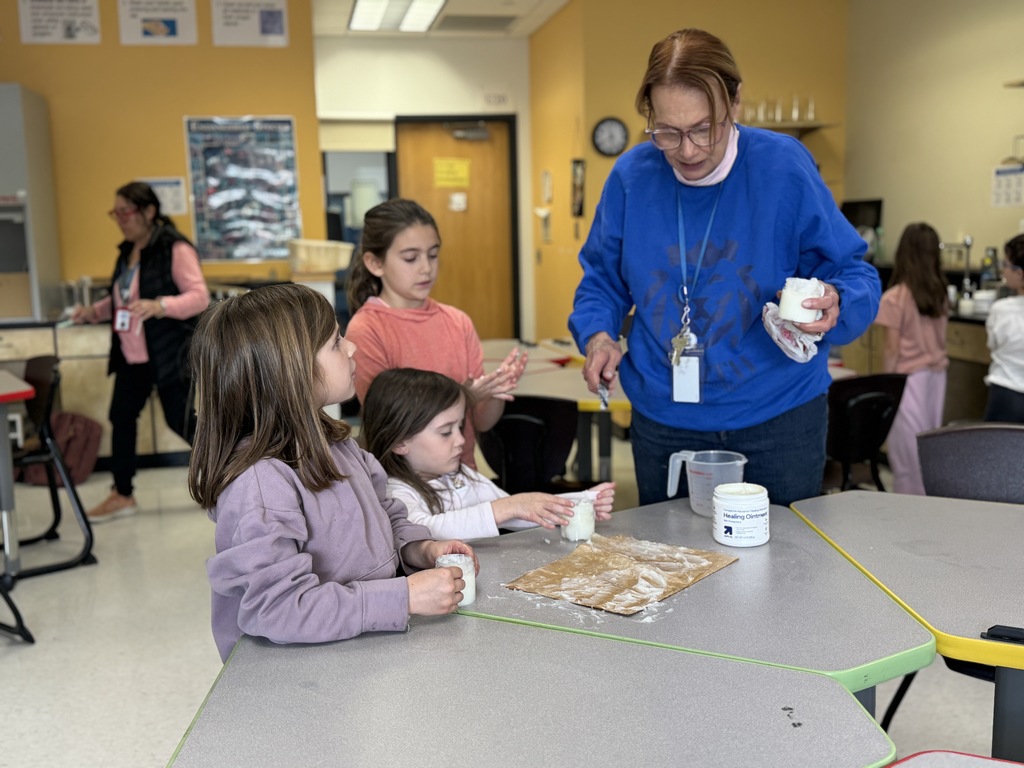 teacher helps students add cream to jars