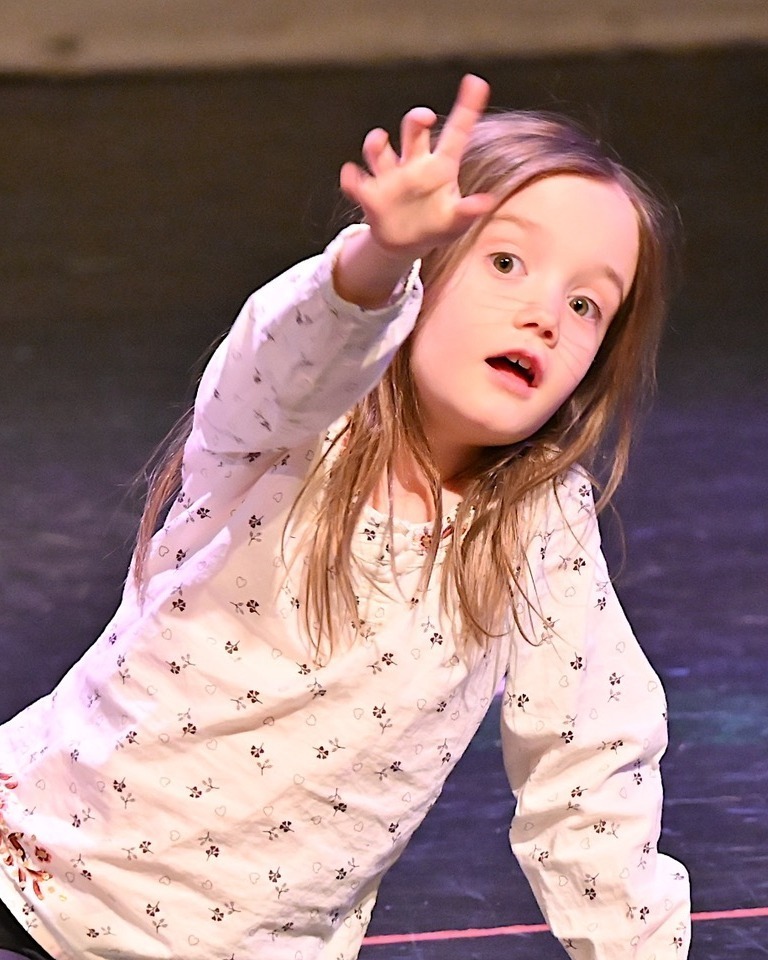 kid sits on stage and reaches out