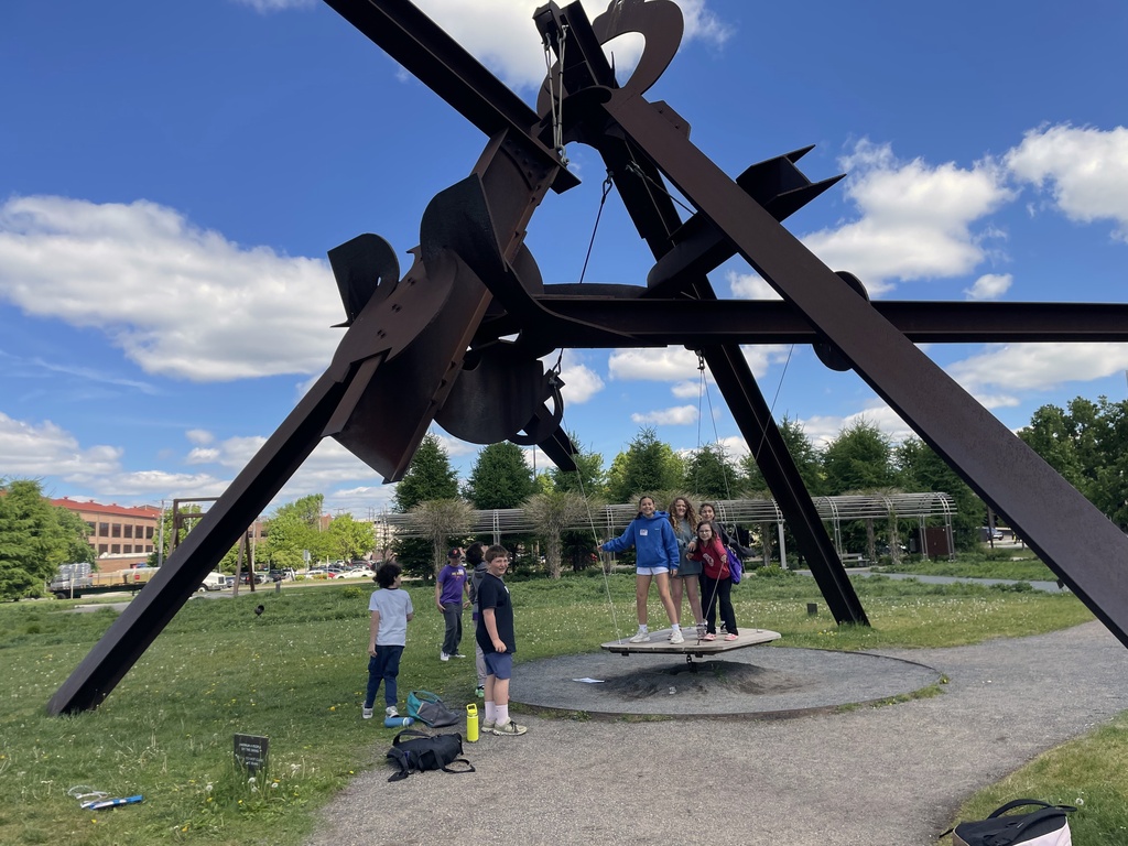 fifth graders stand on Arikidea swing sculpture