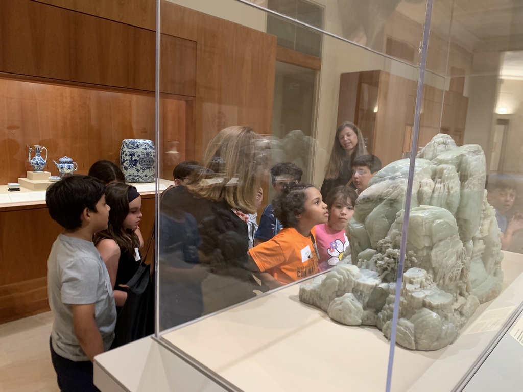 students look at carved sculpture