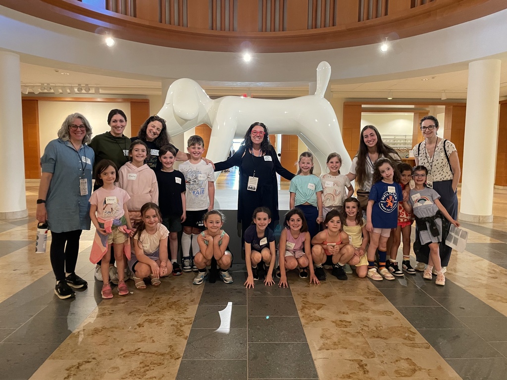 first grade poses in front of giant white dog statue