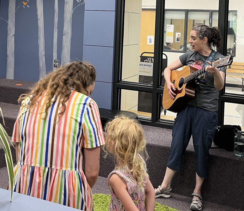 musician sings and plays guitar for attendees