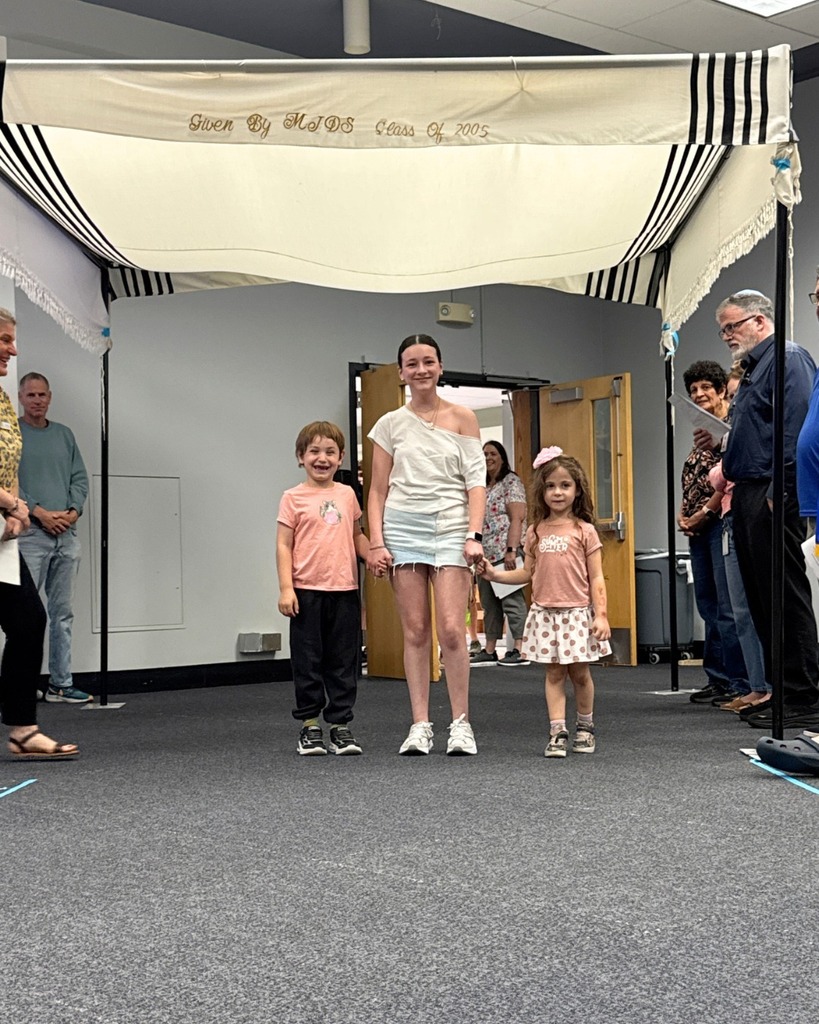 kindergartners walk with eighth grader under chuppah