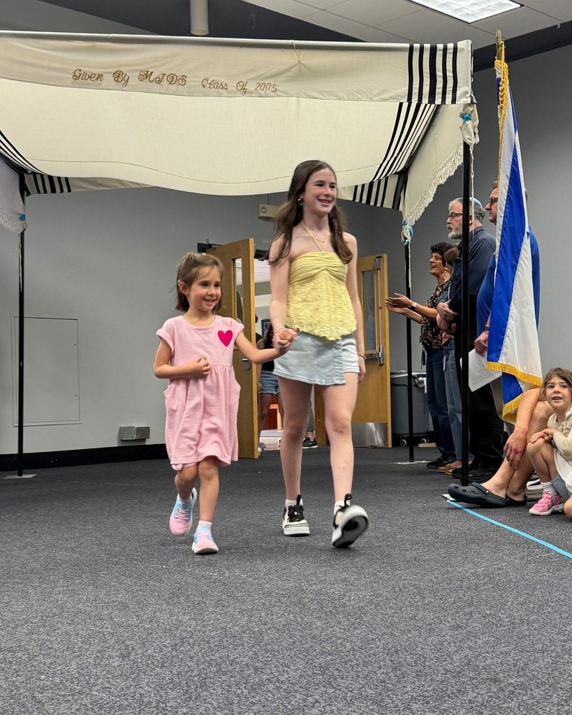 kindergartner walks with eighth grader under chuppah