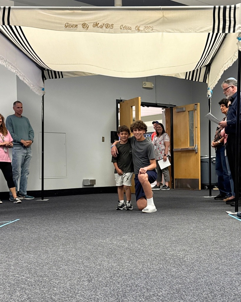 kindergartner poses with eighth grader under chuppah