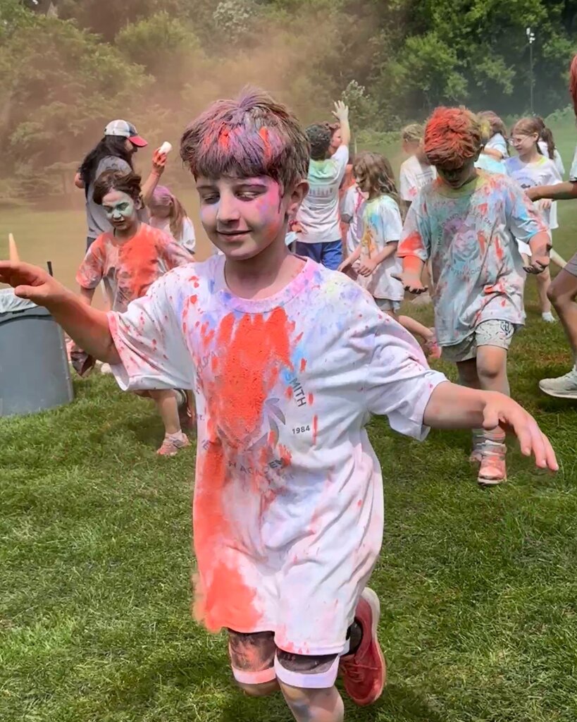 student covered in red chalk runs
