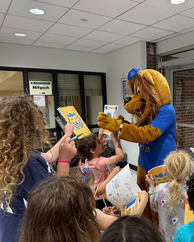 Roary the Lion signs yearbooks for a crowd of students
