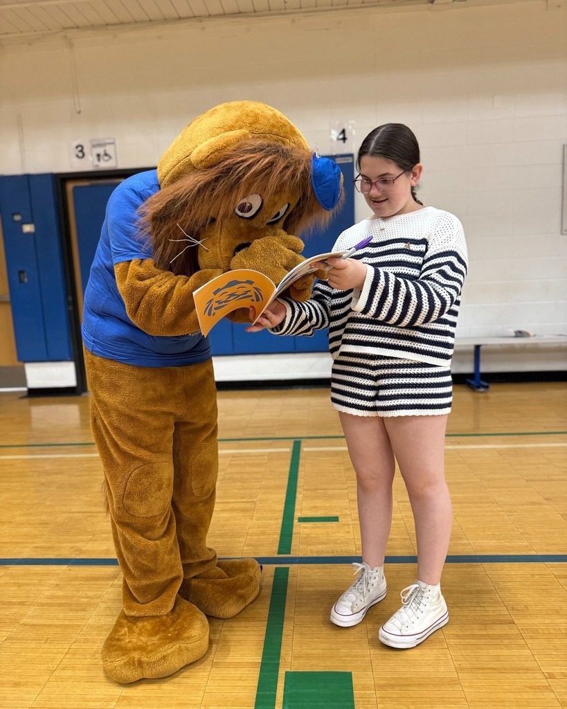 Roary the Lion signs a student's yearbook