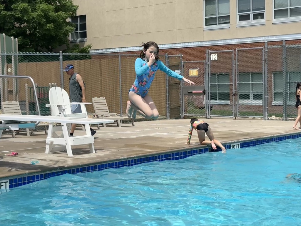 child jumps from diving board into pool