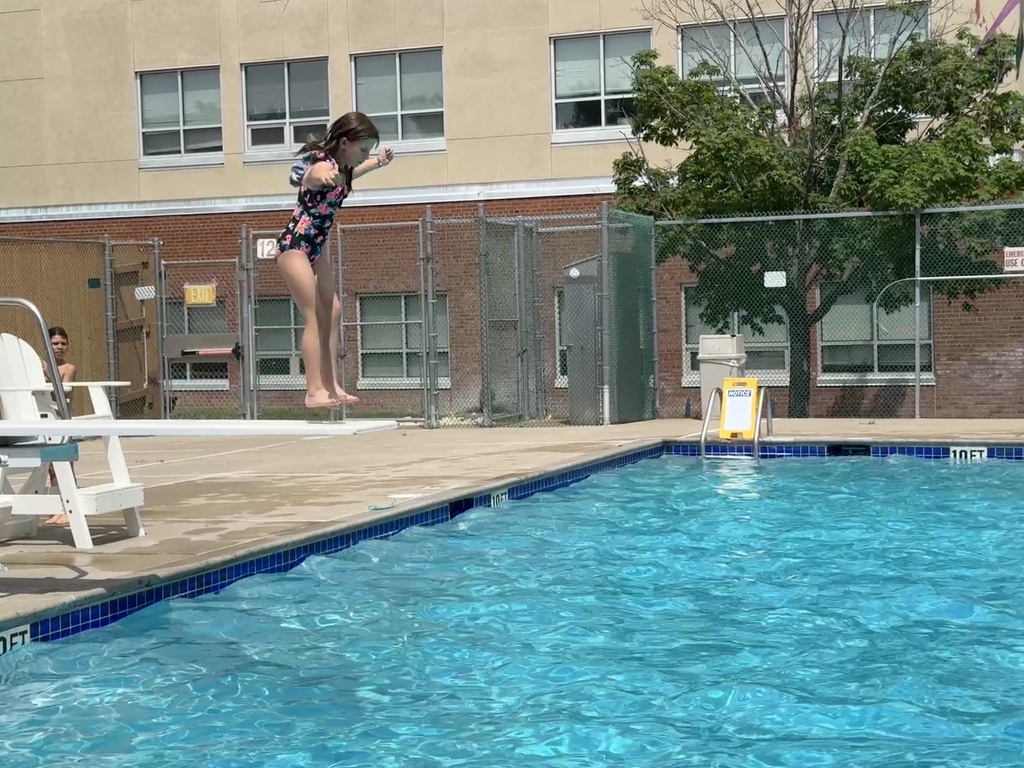 child jumps from diving board into pool