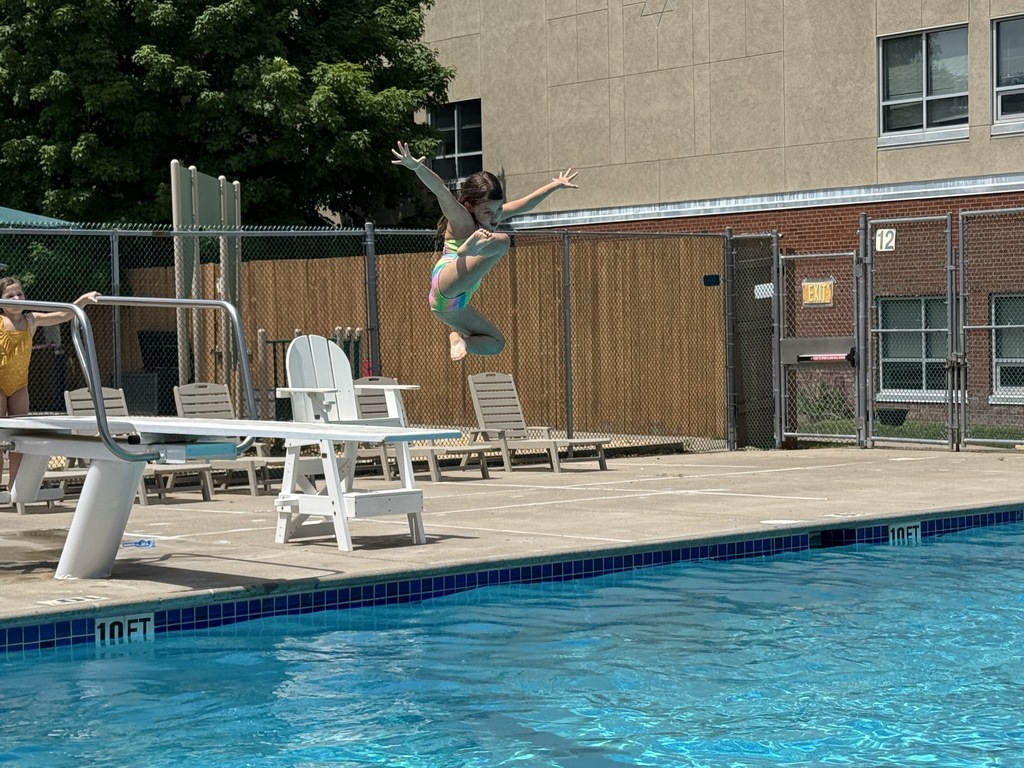 child jumps from diving board into pool