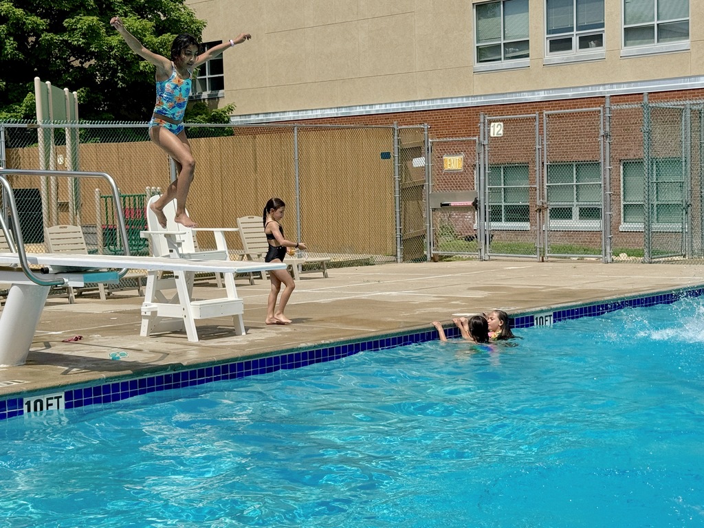 child jumps from diving board into pool