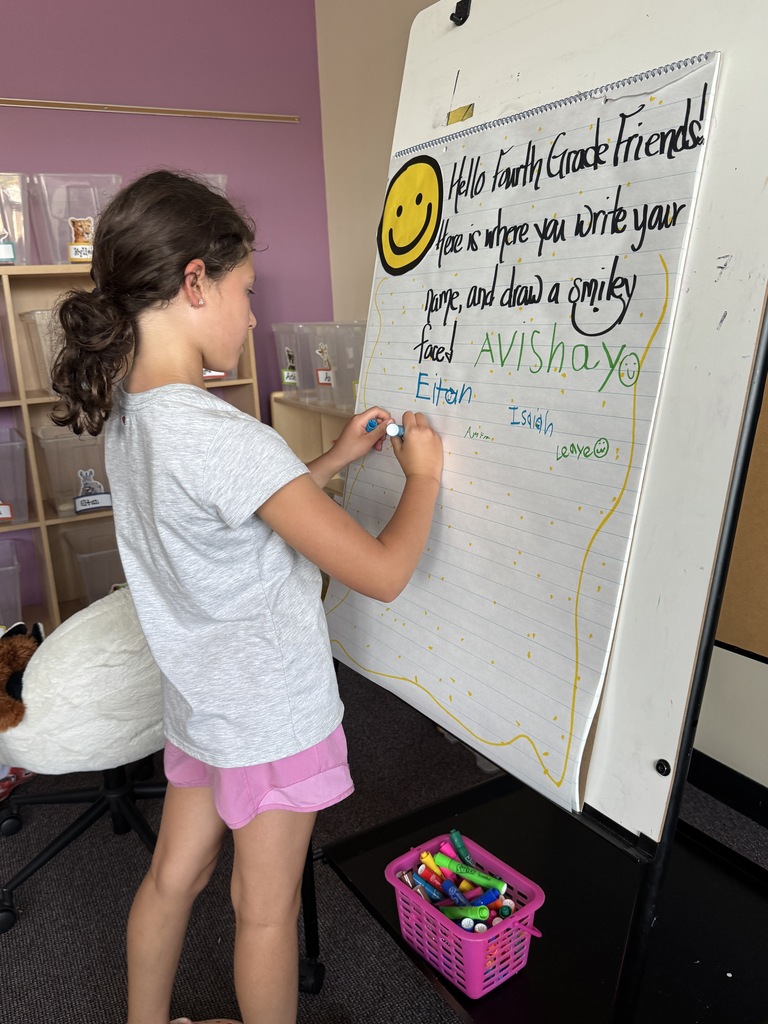 student writes her name on a welcome poster
