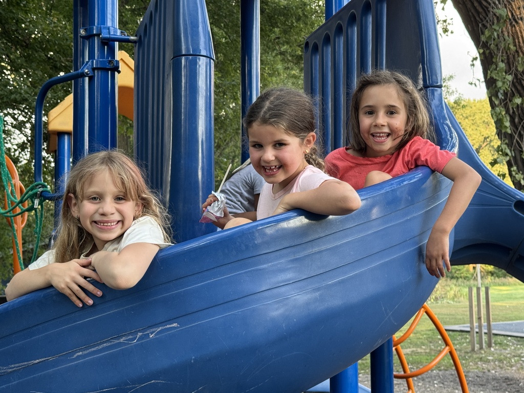 three kids pose going down spiral slide