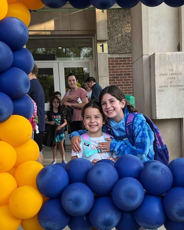 two siblings pose in blue and gold balloon frame