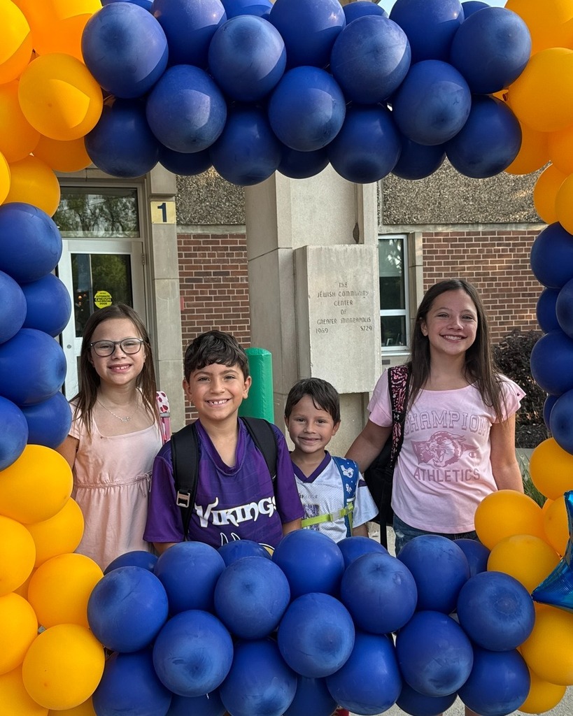 family of four students pose in blue and gold balloon frame