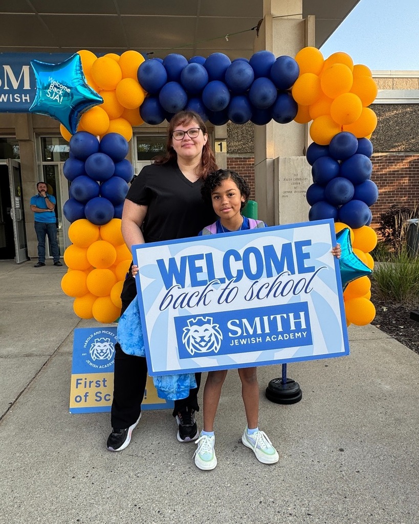 parent and student pose with welcome back to school sign in front of blue and gold balloon frame