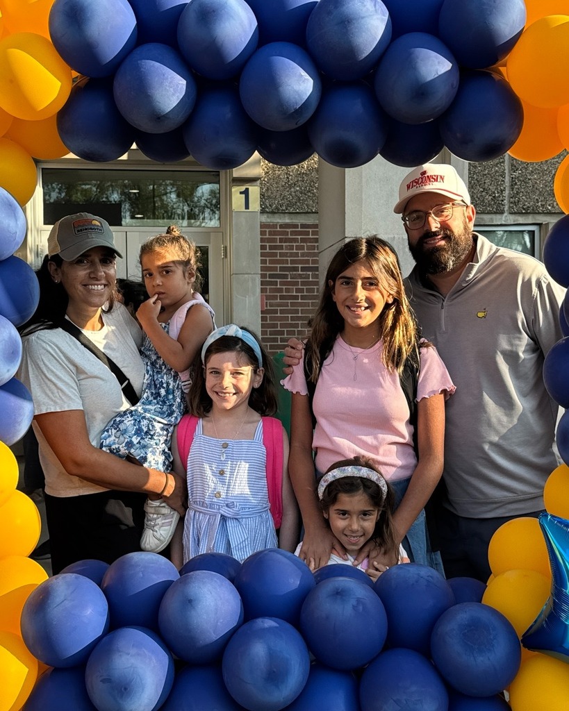 family poses in blue and gold balloon frame