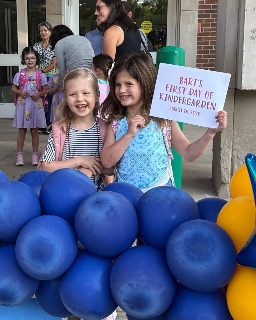two students pose in blue and gold balloon frame