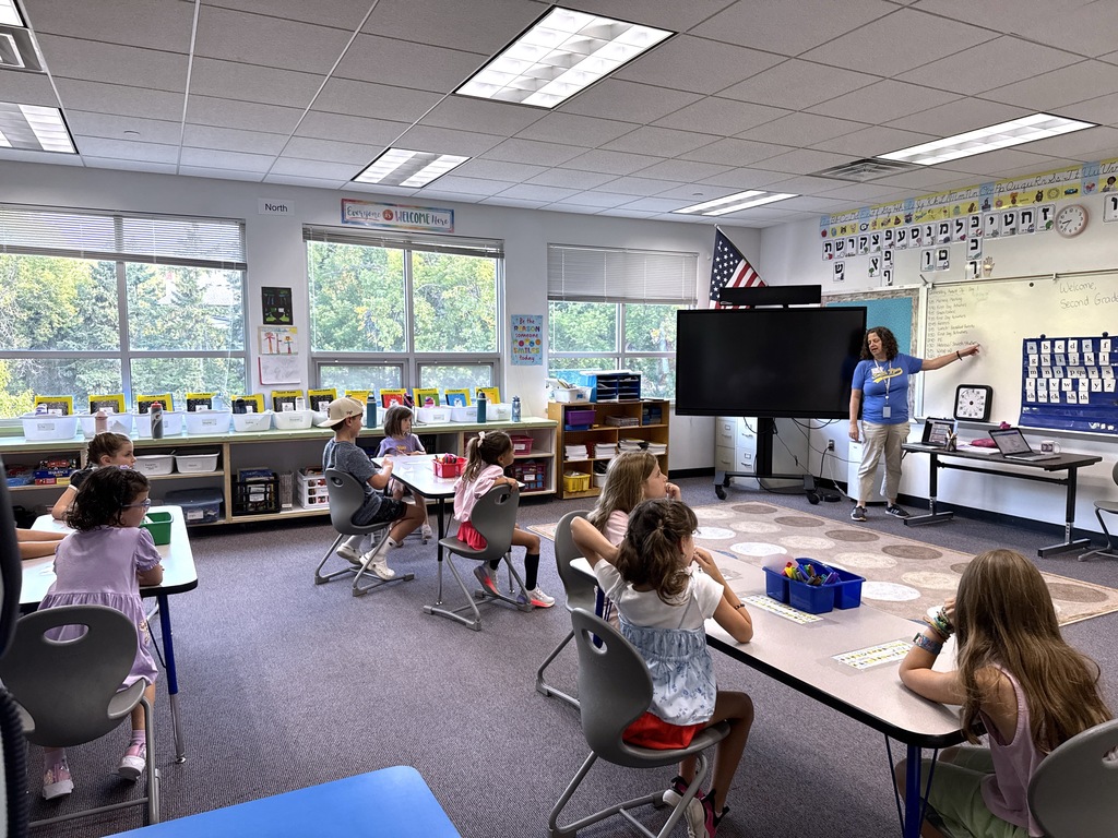 teacher points to white board, students sit at tables
