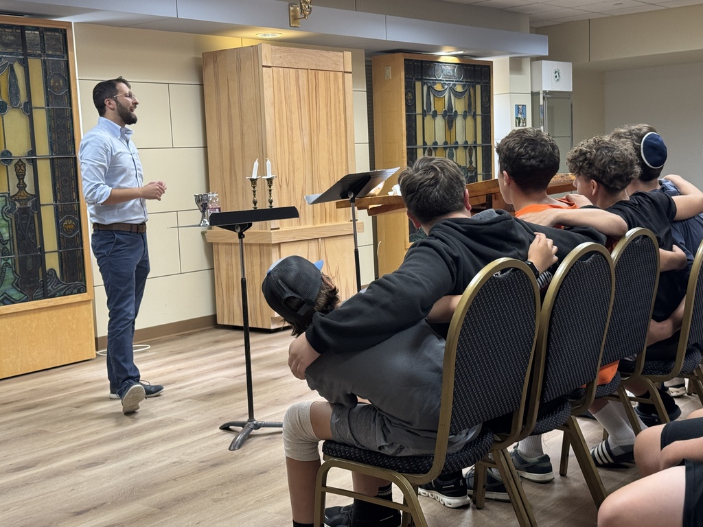 rabbi leads nigun, student sway with arms around one another, shabbat candles ready to be lit