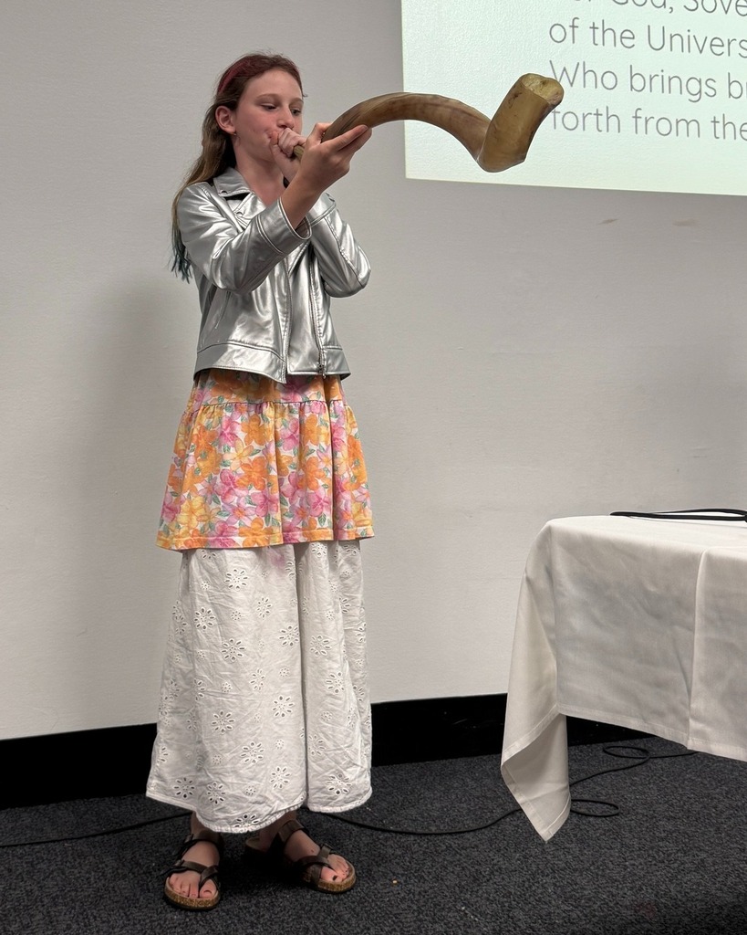 student blows shofar