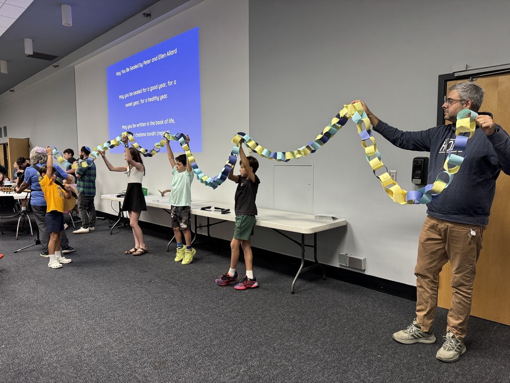 students and teacher hold up completed paper chain
