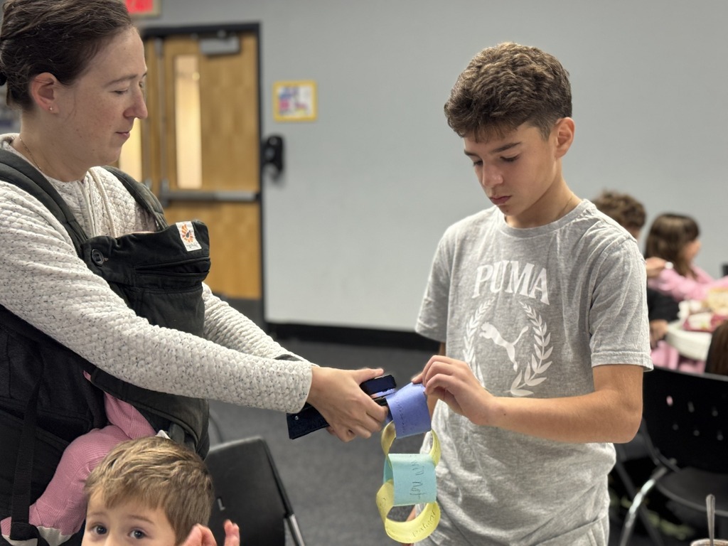 volunteer helps student staple paper chain