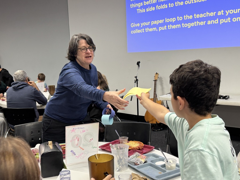 student hands paper to teacher