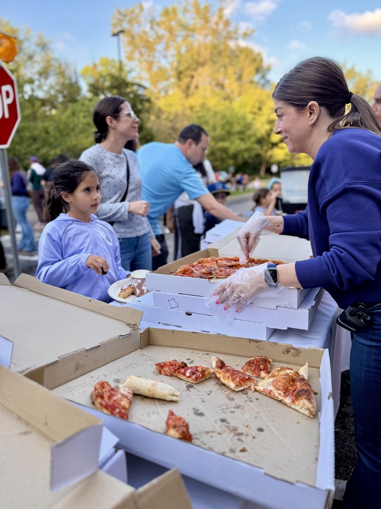 SJA staff member serves pizza to students and families