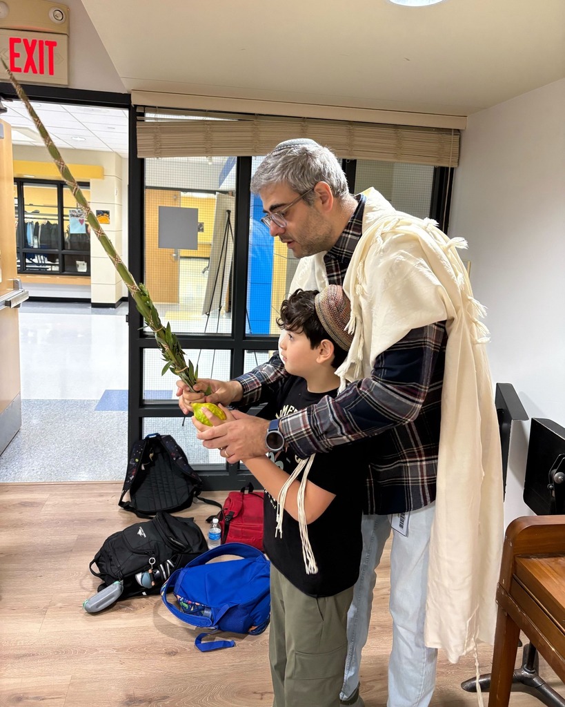 father guides son in shaking lulav and etrog