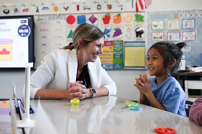 principal sitting and smiling with student at table in classroom