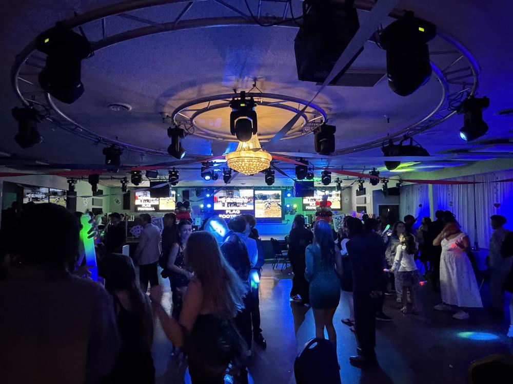 students dance in dark room with party lights