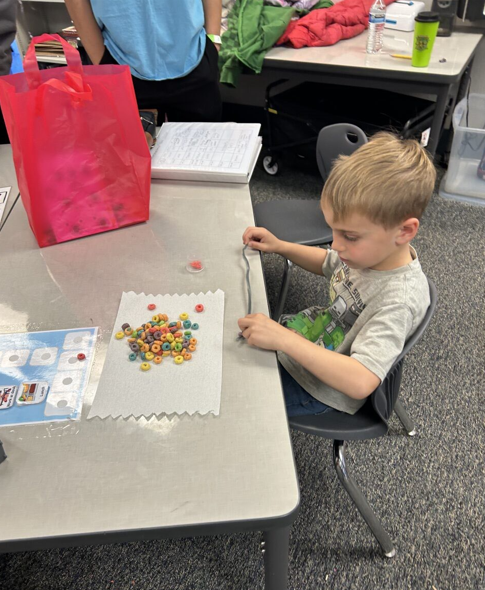 Kinder student creating his fruit loops bracelet. 