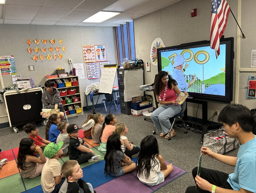 Hamilton High student reading to students on their reading rug