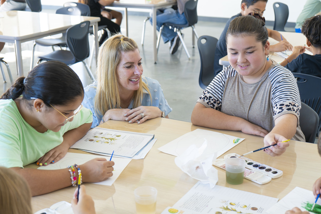 Students working on art with a staff member supporting