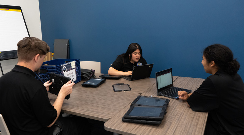 IT intern students working on laptop repairs.