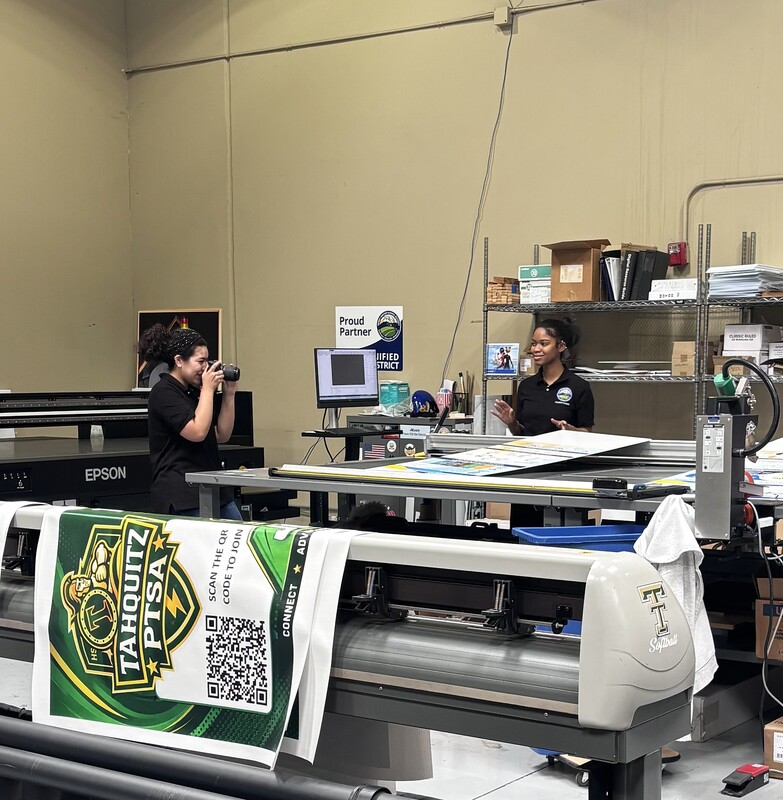 Communications intern photographing Print Shop intern.